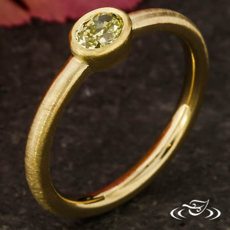 Bezel Ring Holding An Oval Natural Diamond.