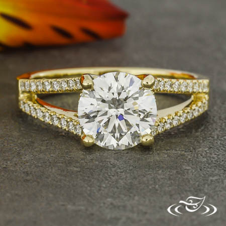 A round diamond with split shank featuring small melee diamonds set in the band.
