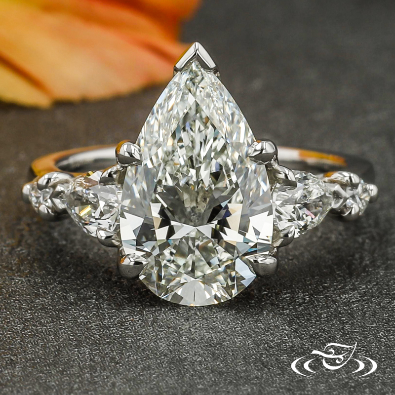 A pear diamond is framed by pear and round diamonds.